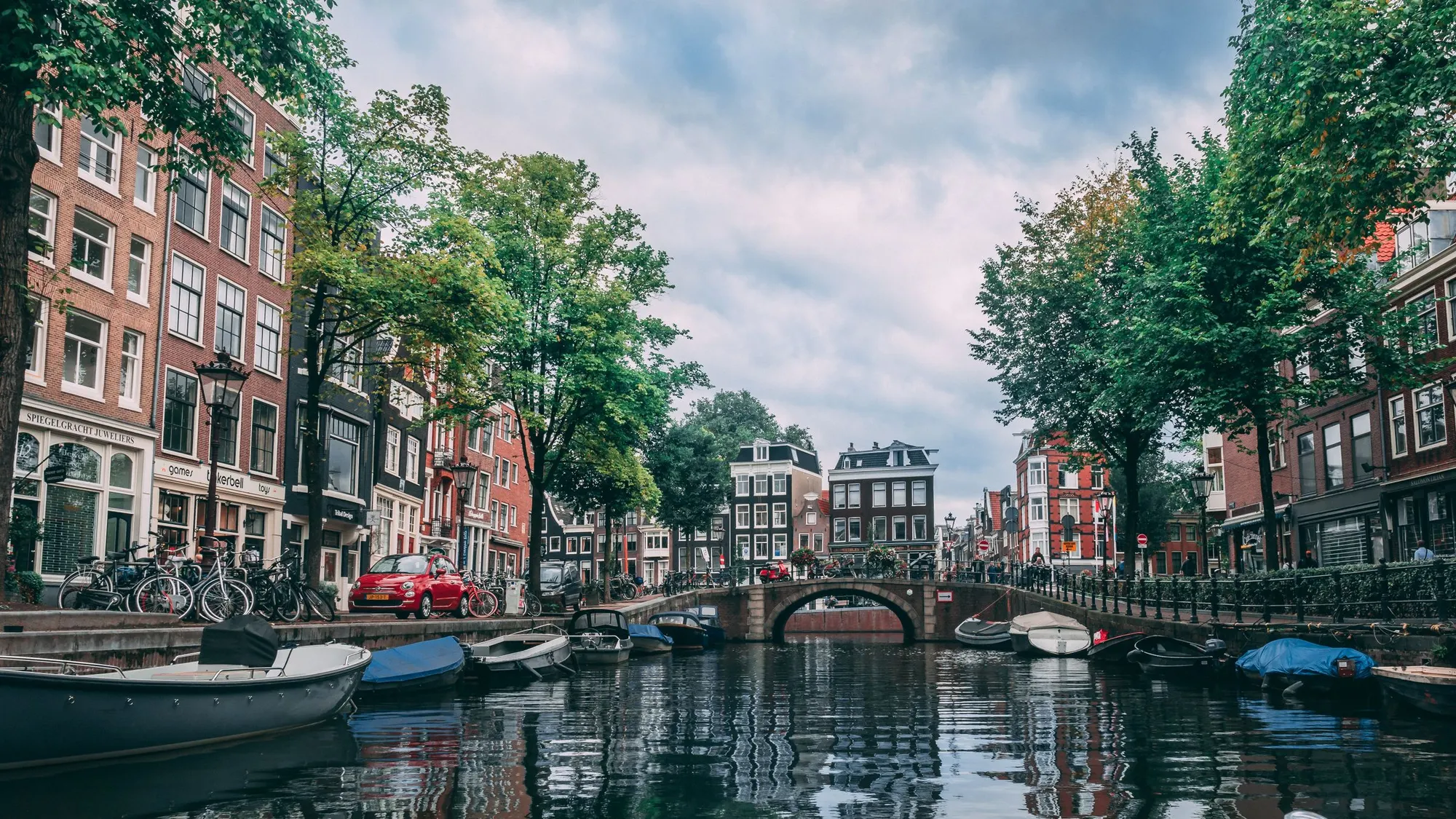 Gracht in Amsterdam met brug, boten en bomen